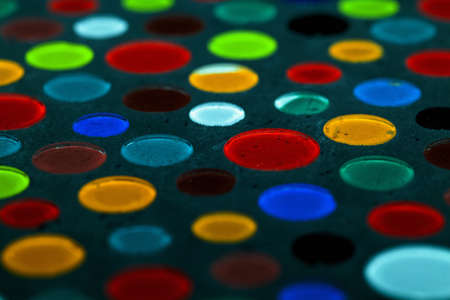 Abstract photo of different colored glass drops in gray concrete.の写真素材