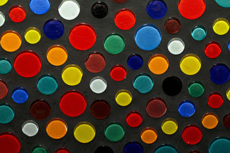 Abstract photo of different colored glass drops in gray concrete.