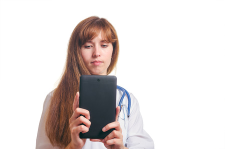 The serious woman the doctor in a white dressing gown photographs the tabletの写真素材