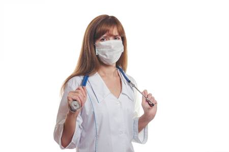 The young woman the doctor in a white dressing gown and a mask with a stethoscope on a neckの写真素材