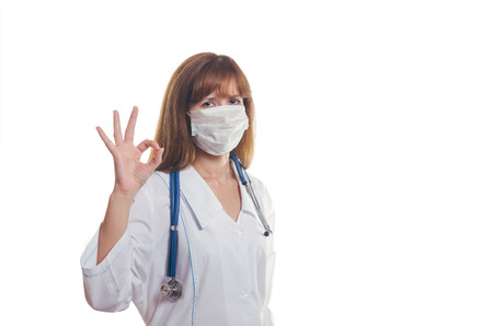 The woman the doctor in a white dressing gown and a mask shows OKの写真素材