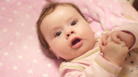 Baby lies in crib.