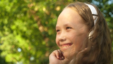 Girl in headphones listening to music and smiling dancing in summer parkの写真素材