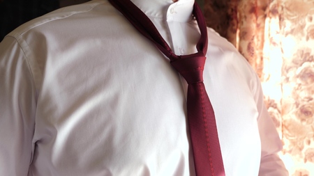 businessman puts on a tie to work in the morning. close-up. man ties up red tie. office worker gets dressed in the morning.の写真素材