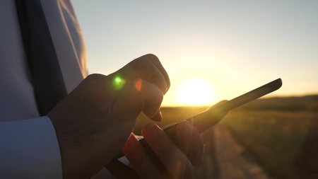 Businessman working on a tablet at sunset. the hands of a man are driving their fingers over the tablet. close-up. man checks email.の写真素材