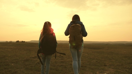 Mom and daughter travel with a backpack against the sky. tourists mother and child go to sunset in the mountains. happy family on vacation travels. sports tourism concept.の写真素材