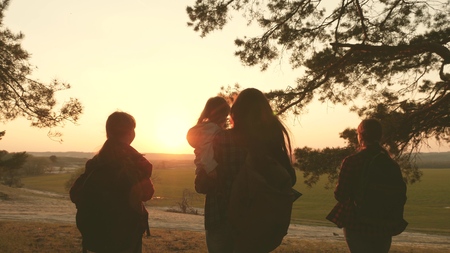 women travel, walk through forest, admire scenery at sunset. Hiker Girl. Tourists rejoice and raise their hands up. travelers mom and travel with backpacks. Family on vacation traveling with a child.の写真素材