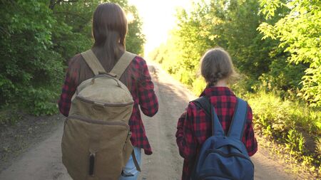 Mom and daughter travel with a backpack against the sky. tourists mother and child go to sunset in the mountains. happy family on vacation travels. sports tourism concept.の写真素材