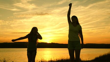 teens girlfriends holiday disco. party by the lake, children dancing. happy girls dancing on the beach. beautiful girls having fun listening to music. sisters are dancing.の写真素材