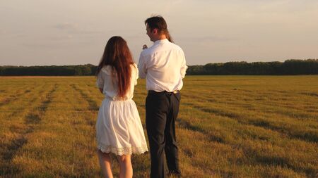 concept of a happy childhood. child, dad and mom play in the meadow in the sun. mother, father and little daughter walking in a field in the sun. Happy young family. concept of a happy family.の写真素材