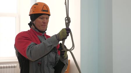 Industrial climber knits a rope for lifting equipment. a worker in a protective helmet knits a knot on a rope.の写真素材