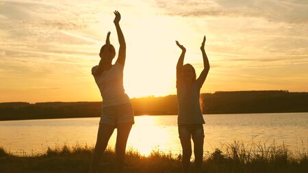 happy girls dancing on the beach. party by the lake, children dancing. beautiful girls having fun listening to music. sisters are dancing. teens girlfriends holiday disco.の写真素材