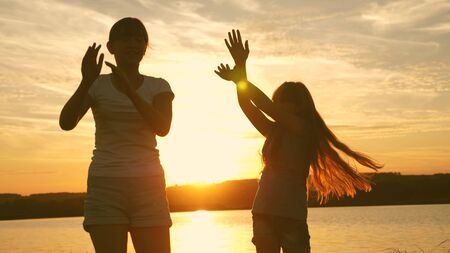 teens girlfriends holiday disco. party by the lake, children dancing. happy girls dancing on the beach. beautiful girls having fun listening to music. sisters are dancing.の写真素材