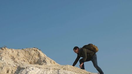 tourists give hand to each other, climbing to top of hill. teamwork of business people. team of male travelers goes to victory and success. climbers climb one after another on white rock.の写真素材