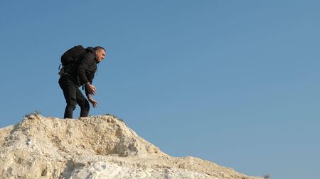 teamwork of business people. tourists give hand to each other, climbing to top of the hill. team of male travelers goes to victory and success. two climbers climb one after another on white rock.の写真素材