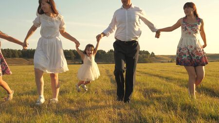 concept of happy family. Children and mom are playing in meadow. mother and little daughter with sisters walking in park. Happy young family with a child walking on summer field. happy family concept.の写真素材