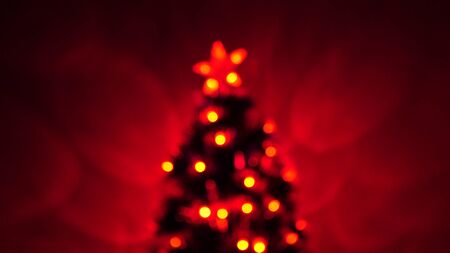 multi-colored bokeh of a New Year tree in the room, decorated with luminous garland and a star. holiday for children and adults. New Year. Christmas tree, happy holidays. Christmas interior.の写真素材