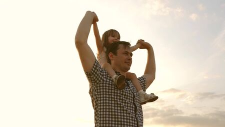 little daughter on fathers shoulders. baby boy and dad travel on a wheat field. The child and parent play in nature. happy family and childhood concept. Slow motionの写真素材