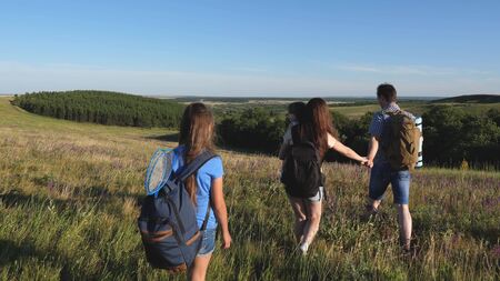 travelers admire the beautiful scenery and nature. teamwork of tourists. travelers go with backpacks through meadow. Family of tourists with children in the countryside. movement to victory.の写真素材