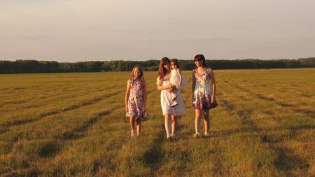 Children and mom are playing in the meadow. concept of a happy family. mother and little daughter with sisters walking in park. Happy young family with a child walking on a summer field.の写真素材