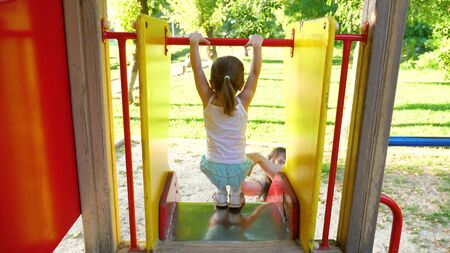 mother and baby play on the playground. little kid laughs and enjoys the playground in the park. child plays with mom on the street.の写真素材