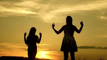 free girls dancing on the beach. party by the lake. beautiful girls having fun listening to music. sisters are dancing. teens girlfriends holiday disco.の写真素材