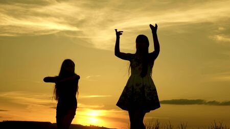 free girls dancing on the beach. party by the lake. beautiful girls having fun listening to music. sisters are dancing. teens girlfriends holiday disco.の写真素材