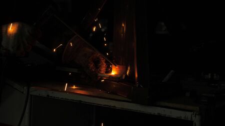 bright light and sparks from welding. Industrial worker in a protective mask using a modern welding machine for welding metal structures in industrial production at a metal processing plant.の写真素材