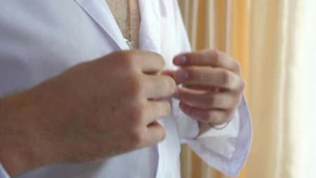 Mens hands fasten buttons on a white shirt. a man puts on clothes in morning to work. office worker....
