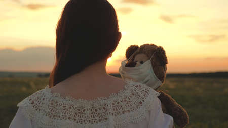 A child holds his beloved teddy bear in a protective maskの写真素材