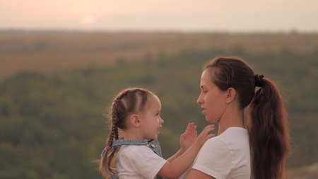 mommy and baby hug. Mom plays with her daughter and shows child sunset. Happy family, mom and daughter in field look at sun. concept of a happy family and healthy children. baby loves mommyの写真素材