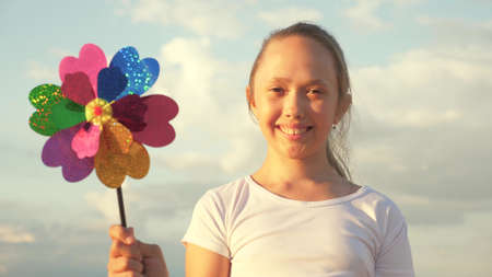 girl playing pinwheel park in slow motion. Happy child playing having fun pinwheel. Happiness vacation childhood children happy family holiday. childhood concept. a child playing in park catches windの写真素材