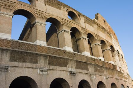 The roman Coliseum in a sunny day. Blue sky. Famous ancient construction in Italy. It has a large history and now is an icon of the Roman region and a new candidate of the seven wonders.の写真素材