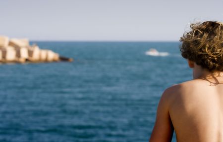 Boy sunbathing and looking the channel of the port of Torrevieja, Spain.の写真素材