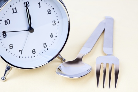 Clock with some silverware on the tableの写真素材