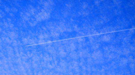 Contrail visible through the clouds of the blue skyの写真素材