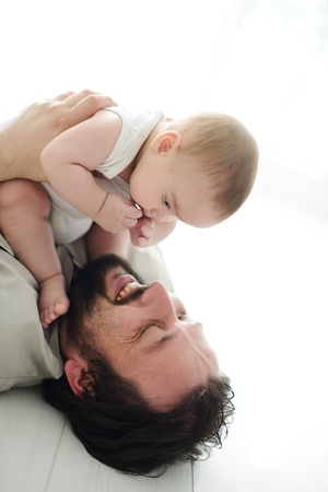 Young father lying on floor at home and playing with adorable babyの写真素材