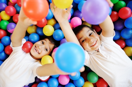 Happy children playing together and having fun at kindergarten with colorful ballsの写真素材