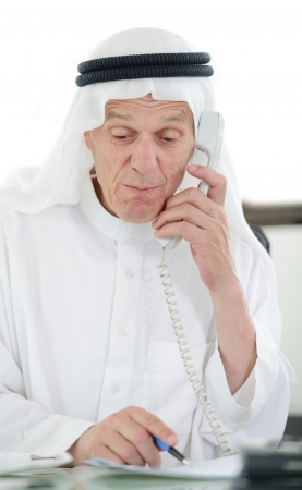 Portrait of a smart arabic business man using laptop and talking  on the phoneの写真素材