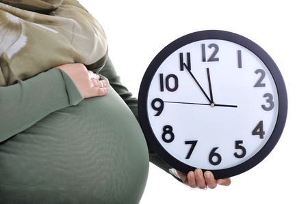 Tummy of pregnant muslim woman with clockの写真素材