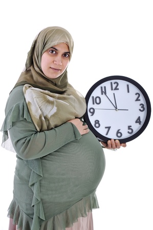 Tummy of pregnant muslim woman with clockの写真素材