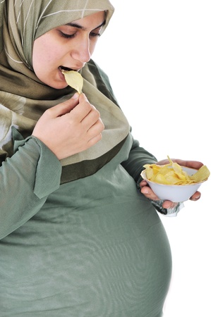 pregnant pretty muslim woman eats chipsの写真素材