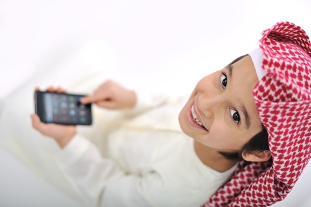 Kid with traditional middle eastern clothes playing with smart phone