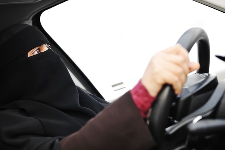 Arabic Muslim woman with veil and scarf (hijab and niqab) driving carの写真素材