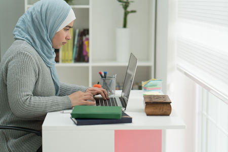 Young Muslim Girl Wotking on Laptop on Deskの写真素材