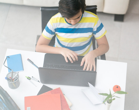 a young boy sitting on laptop at the deskの写真素材