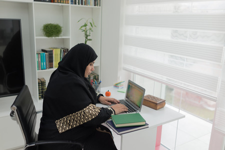 Young Muslim Girl Wotking on Laptop on Deskの写真素材