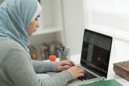 Young Muslim Girl Wotking on Laptop on Desk