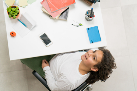 Young boy sitting at working desk looking upの写真素材