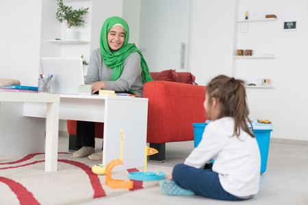 Home Working Single Muslim Mother Taking Care of Childの写真素材